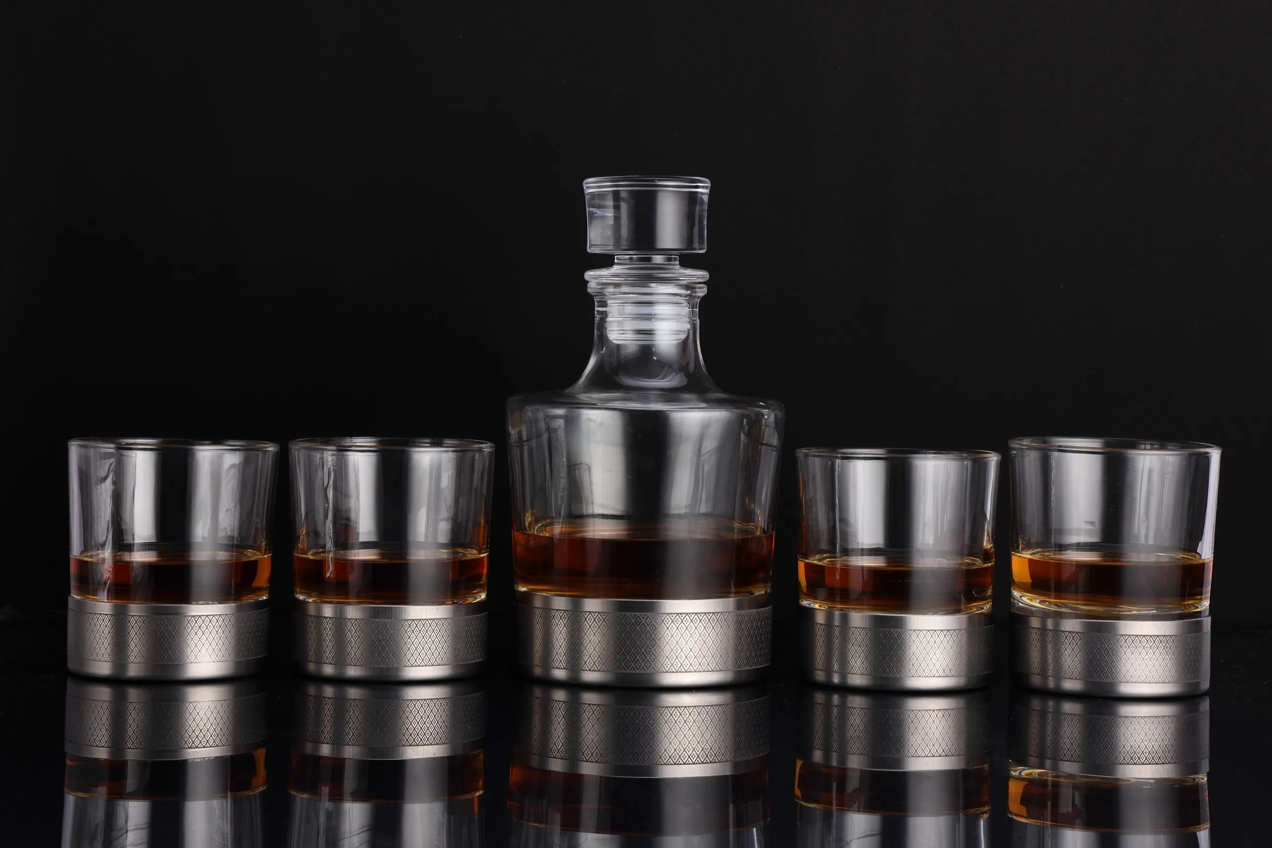 The full set: a decanter flanked by four whiskey glasses, all on titanium bases