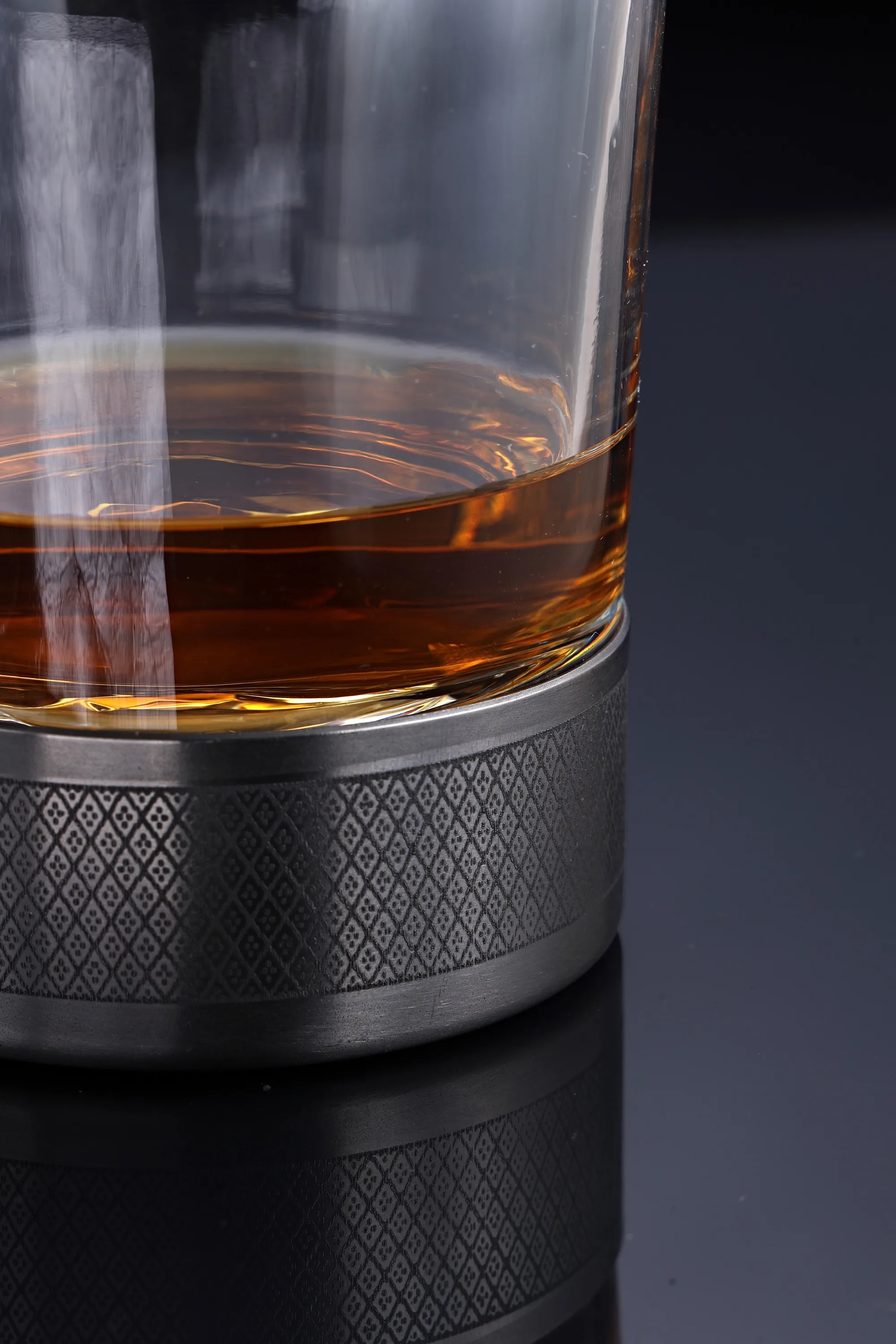 Close-up of a glass of whiskey resting in a diamond-knurled titanium base